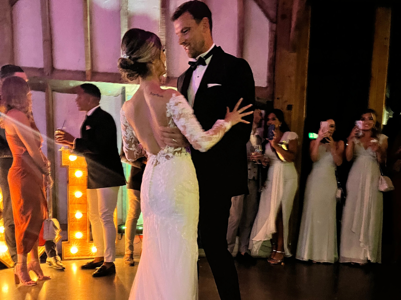 Bride and groom sharing their first dance on a starlit dancefloor with light-up letter decor
