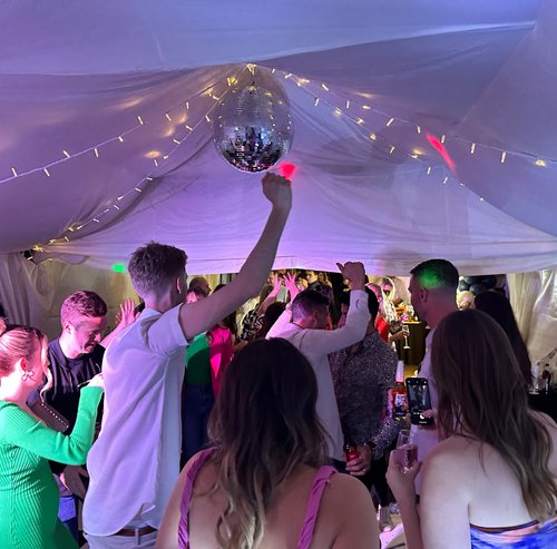 1 Guests dancing under a mirror ball beneath festoon-lit marquee drapes
