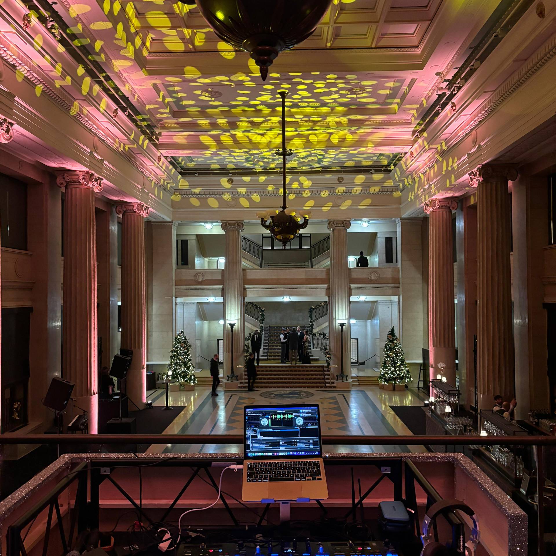 2 DJ booth set up with laptop overlooking a grand hotel atrium decorated for a Christmas party