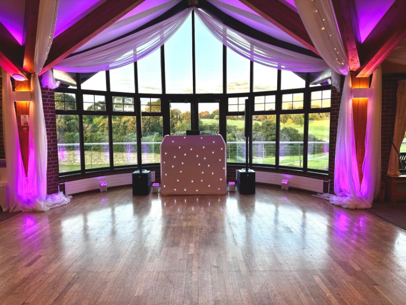 White LED starlit dancefloor and DJ booth set up in a venue with panoramic garden views