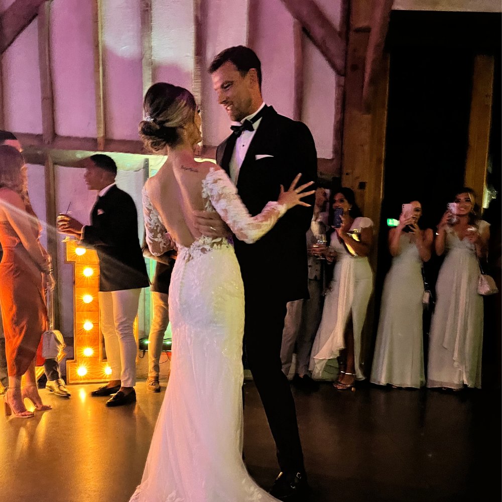 4 Bride and groom sharing a first dance in a barn wedding venue with light-up letter decor in the background