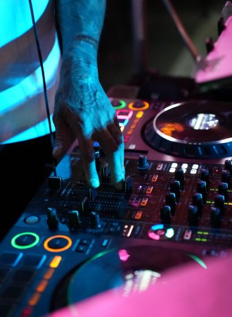 Close-up of a DJ mixing on professional decks with coloured lighting