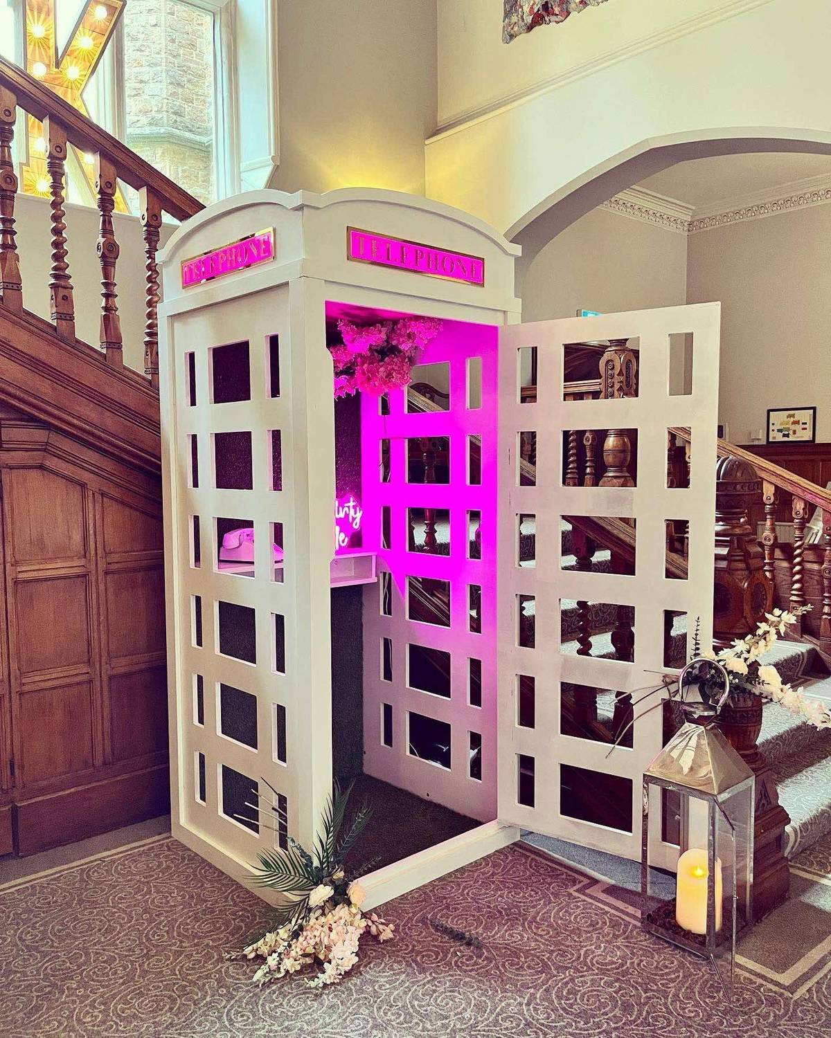 IMG_3871 Bespoke pink neon-lit telephone box photobooth with floral styling at a wedding venue staircase