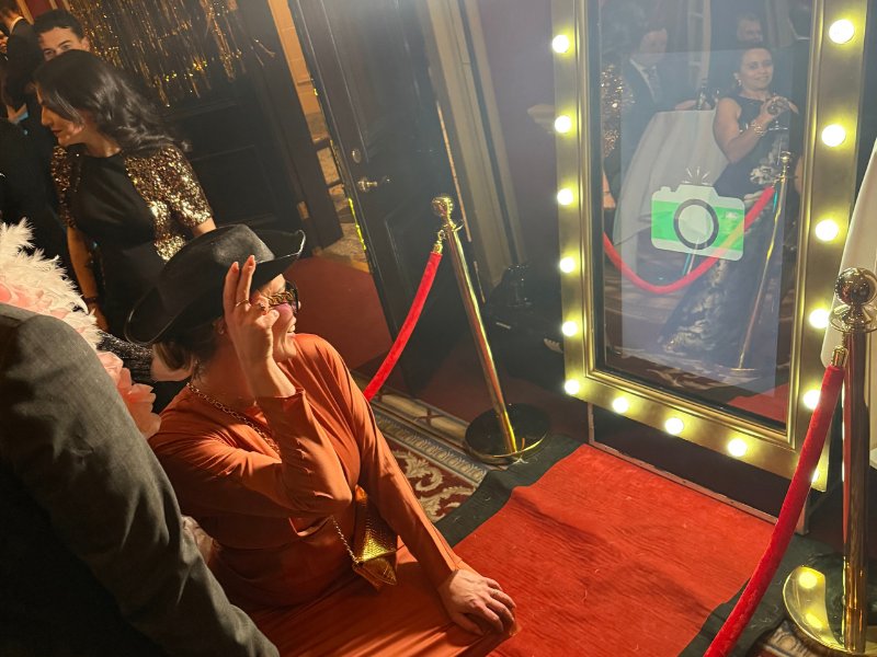 Guests posing in front of a magic mirror photobooth with a red carpet and ropes