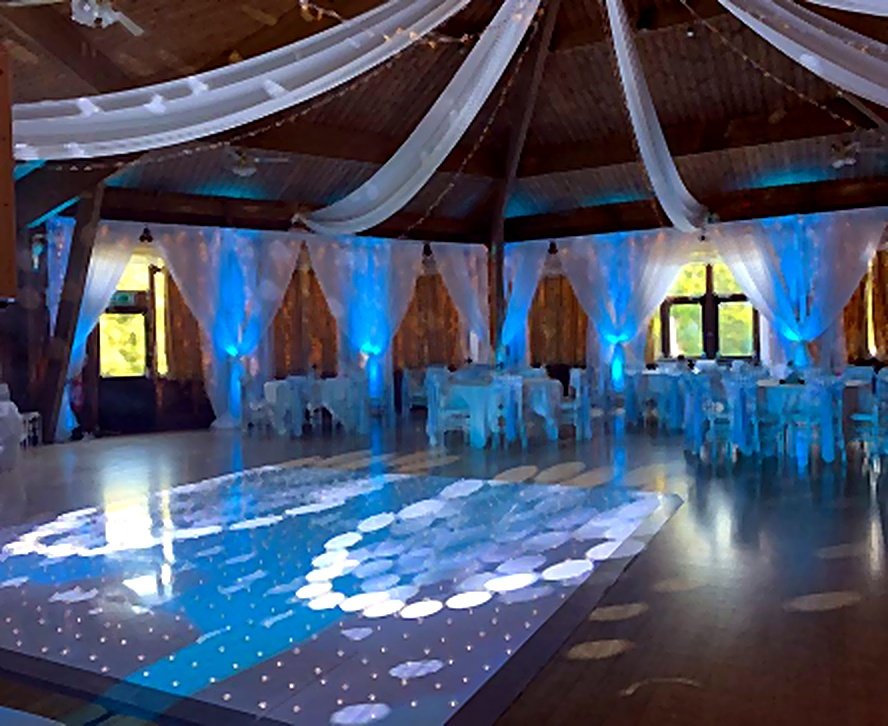 Wedding reception room styled with blue venue uplighting