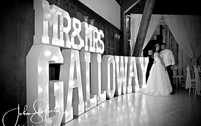 Bride and groom dancing beside illuminated MR AND MRS letters