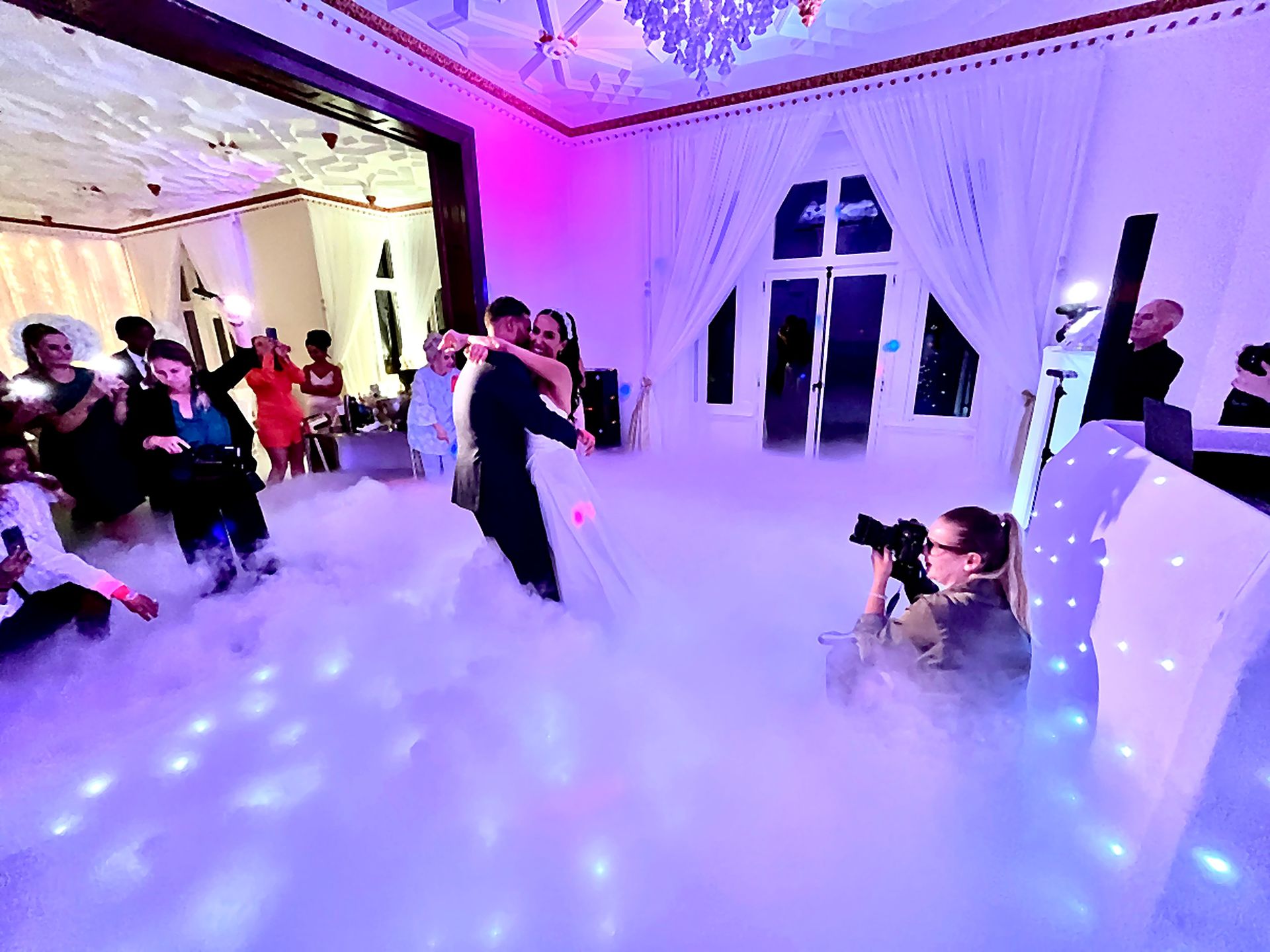 Guests cheering as the couple share a first dance in dry ice cloud effect